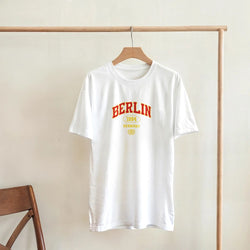 White women's Berlin graphic T-shirt with red BERLIN arch and yellow 1994 Germany print.