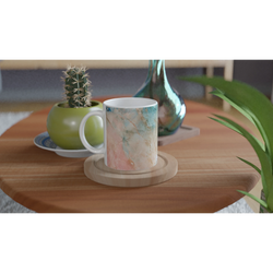 Pastel marble ceramic mug in peach and aqua abstract pattern on a wooden table beside a cactus.