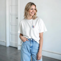 Woman wearing white Vintage Palm Tree Graphic T-shirt for Women; tropical beach tee with small palm logo.