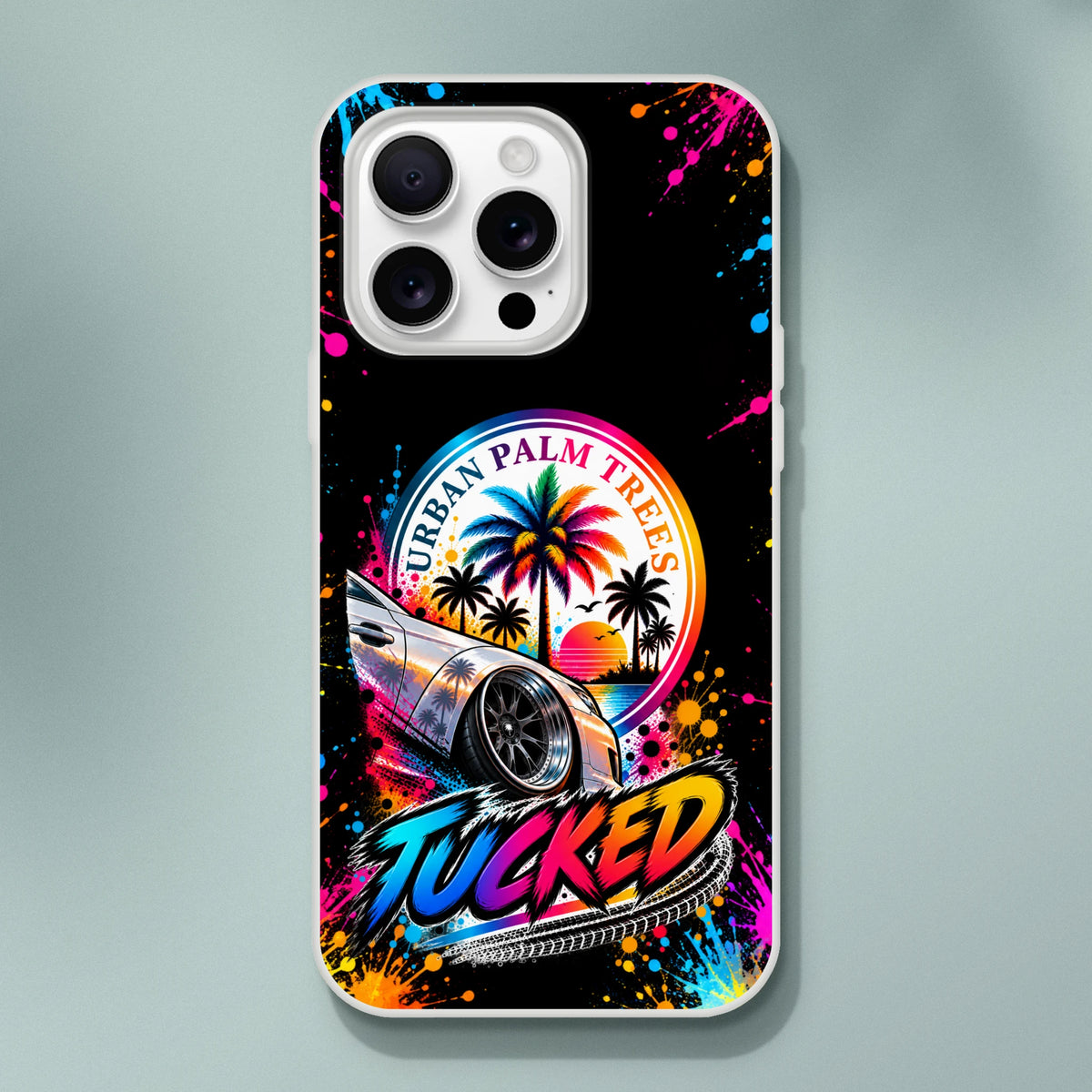 Tucked stance iPhone case featuring lowered car, Urban Palm Trees sunset graphic, and colorful paint splatters on black background.