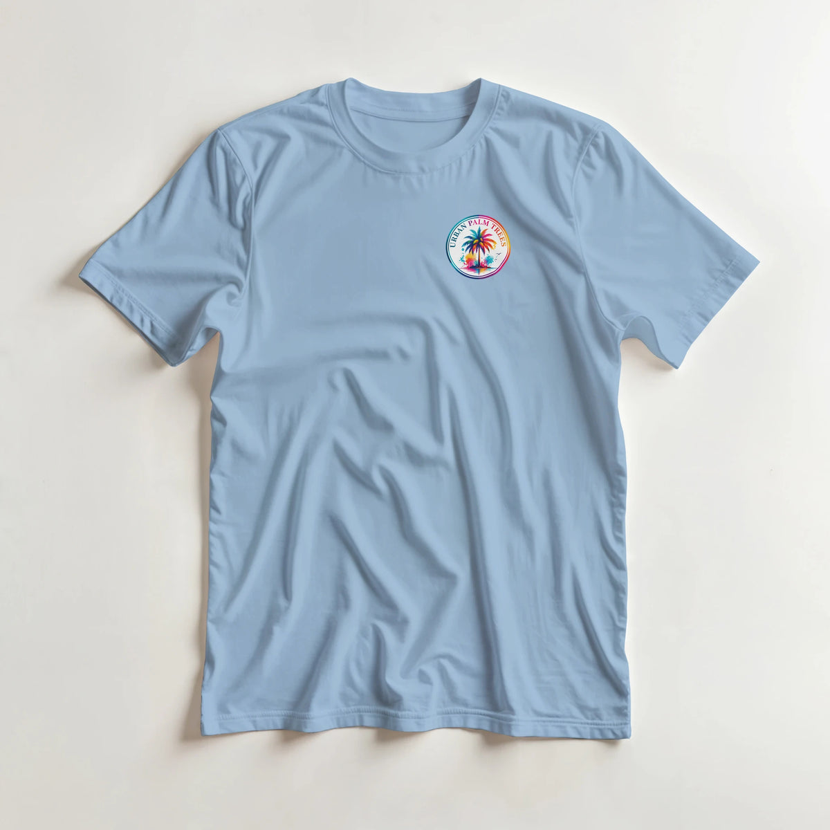 Light blue crew neck t-shirt featuring a colorful circular Urban Palm Trees logo on the left chest.