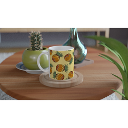 Cute pineapple-pattern mug—tropical fruit coffee cup on a wooden table beside a cactus and green vase.