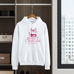 White hoodie with 'Sweet Cherries' design on a hanger in a room with shelves and a window.