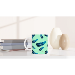 Blue Feather Mug - Mint Green Aesthetic Coffee Cup with blue feather pattern on a white desk.