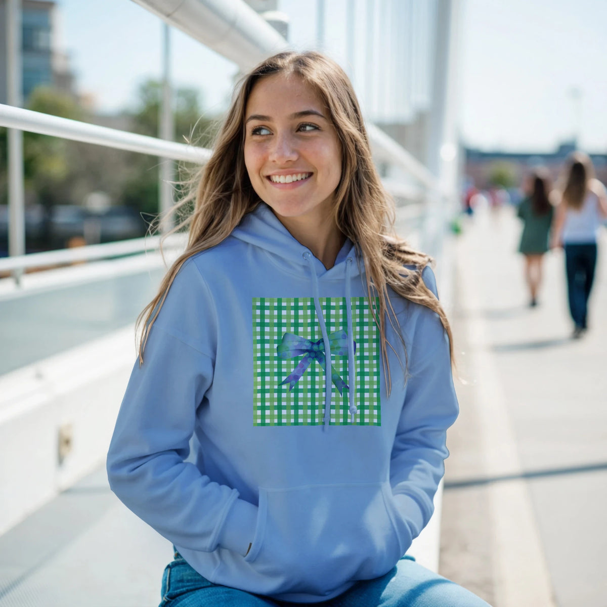 Light blue pullover hoodie featuring a green gingham square and purple bow graphic for a cute coquette aesthetic streetwear look.
