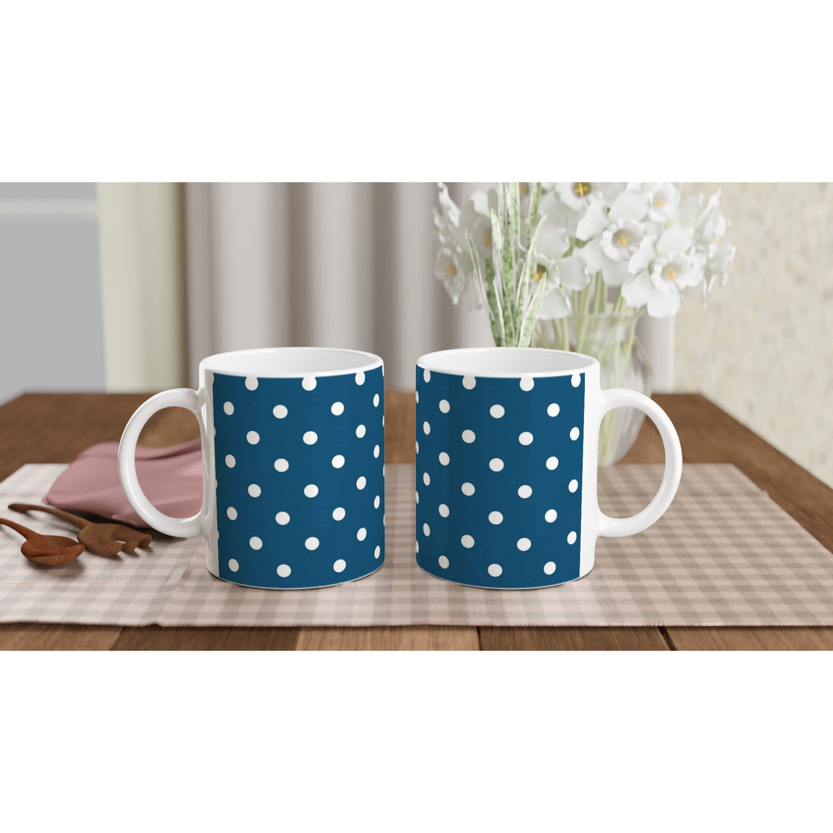 Navy blue and white polka dot ceramic coffee mugs with retro spotty print on a checkered placemat.