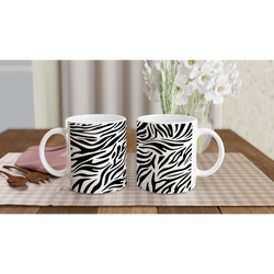 Black and white zebra-print mugs on a checkered table, bold animal-print coffee cups.