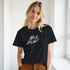Female model wearing black Wild Heart T-Shirt with retro slogan in a sunlit corridor.