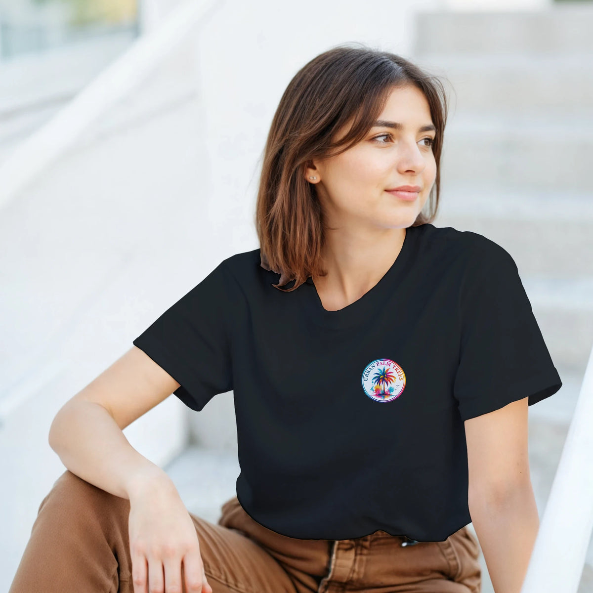 Woman wearing black crew neck t-shirt featuring colorful circular Urban Palm Trees graphic on the chest.