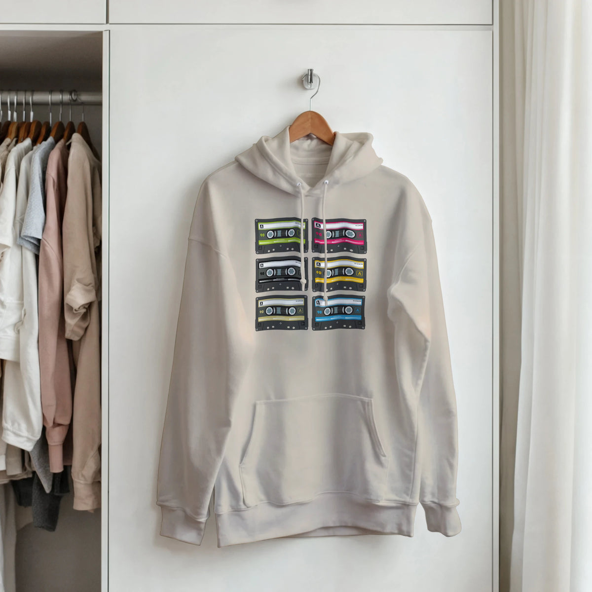 Beige pullover hoodie featuring a grid of six colorful vintage cassette tape graphics on the front.