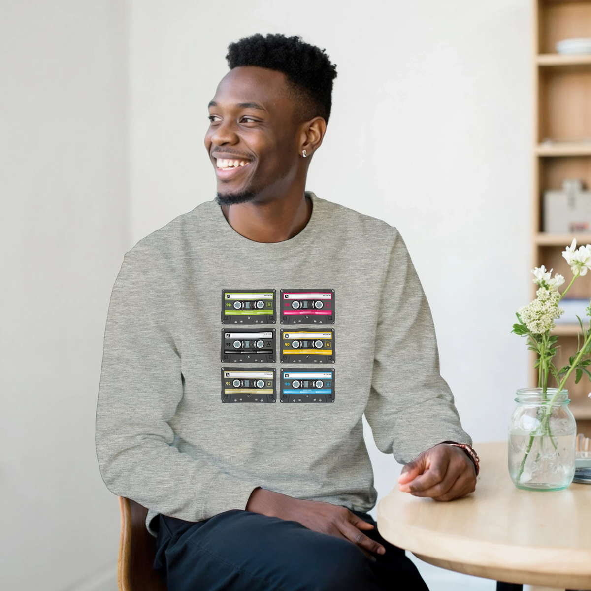 Man wearing a grey vintage 90s cassette tape sweatshirt featuring six colorful audio graphic designs for retro streetwear style.
