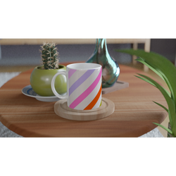 Pastel diagonal-striped ceramic mug with rainbow hues on a wooden table beside a cactus.