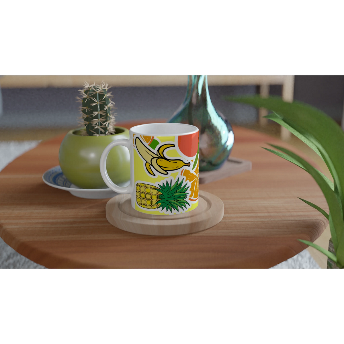 Vibrant ceramic coffee mug featuring banana, pineapple, and orange illustrations on a wooden table with a cactus.