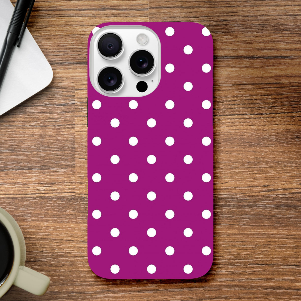 Purple and white polka dot tough iPhone case with shock-absorbing TPU protection for models 13 through 16 on a wooden surface.