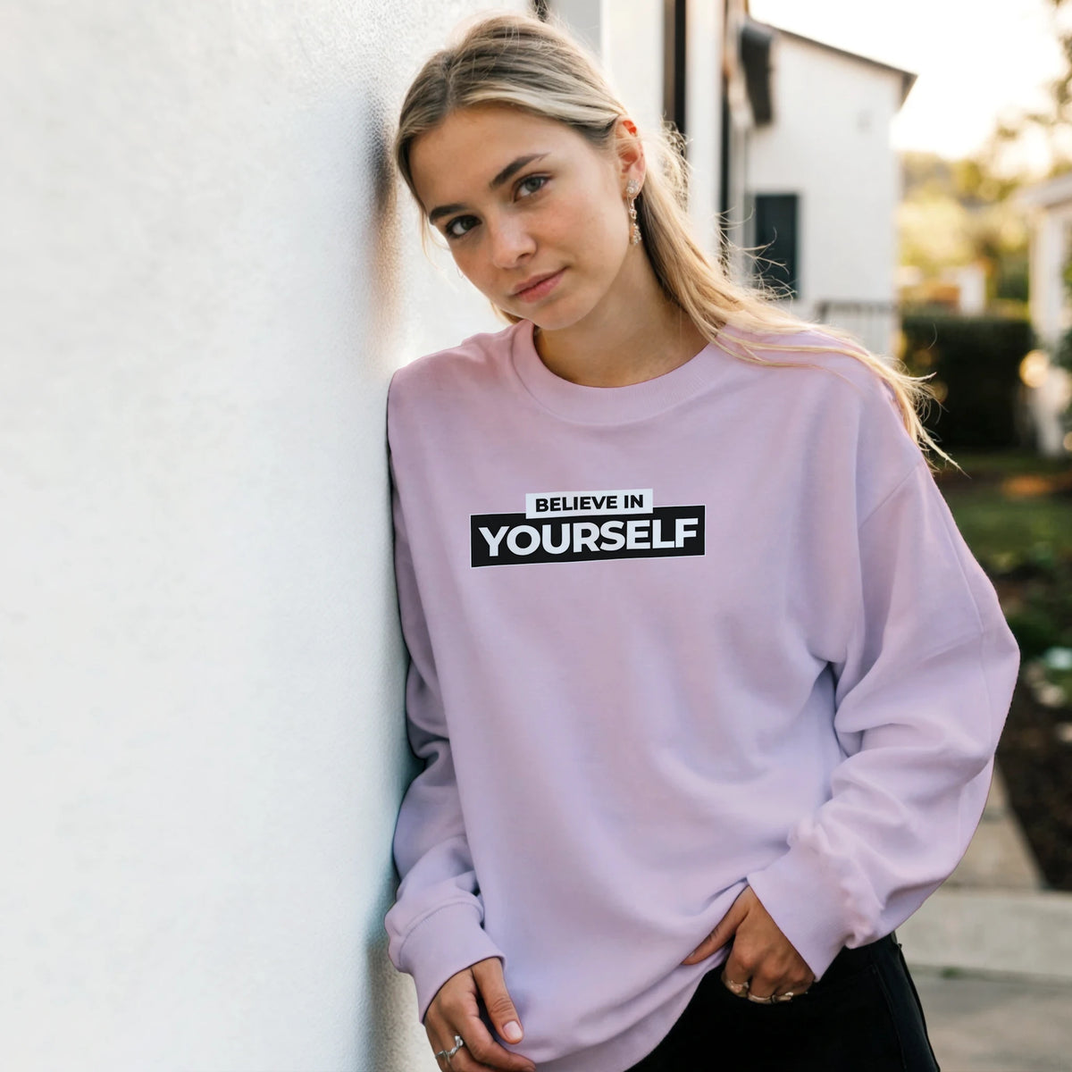 Woman in lavender Cute Believe In Yourself sweatshirt with bold 'BELIEVE IN YOURSELF' slogan.