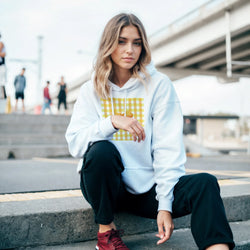 Woman in light-blue hoodie with a yellow gingham bow graphic, stylish coquette streetwear vibe.