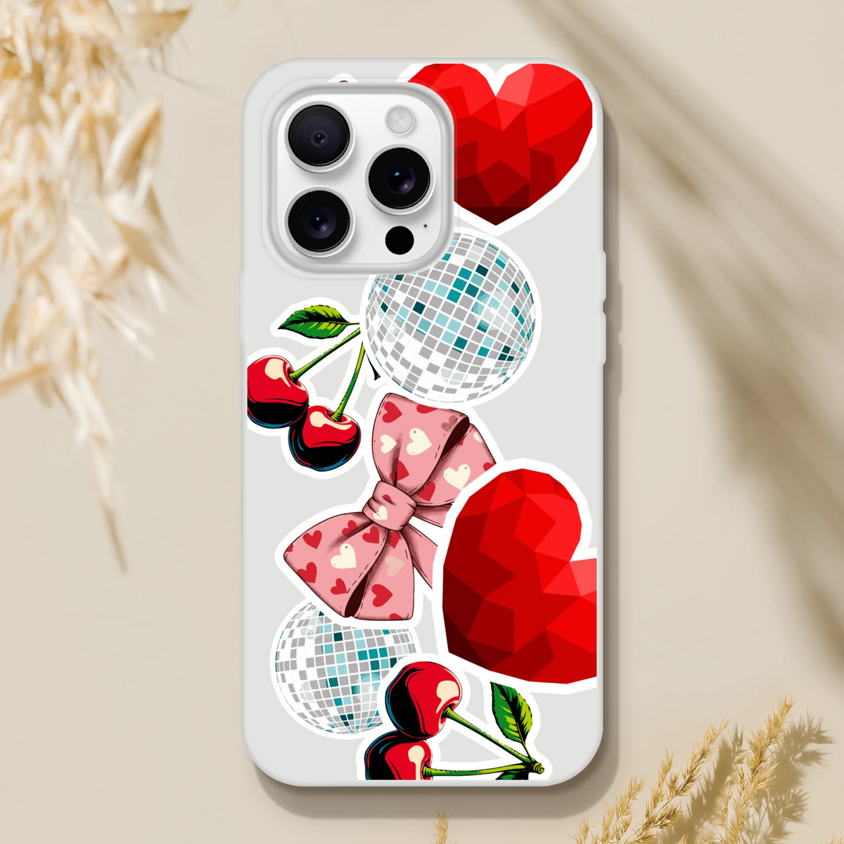 Y2K sticker style iPhone case featuring disco balls, glossy red hearts, cherries, and a pink bow pattern on a clear shell.