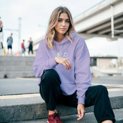 Woman wearing Cute Wild Heart Hoodie in lavender, a cozy slogan top for women, urban streetwear.