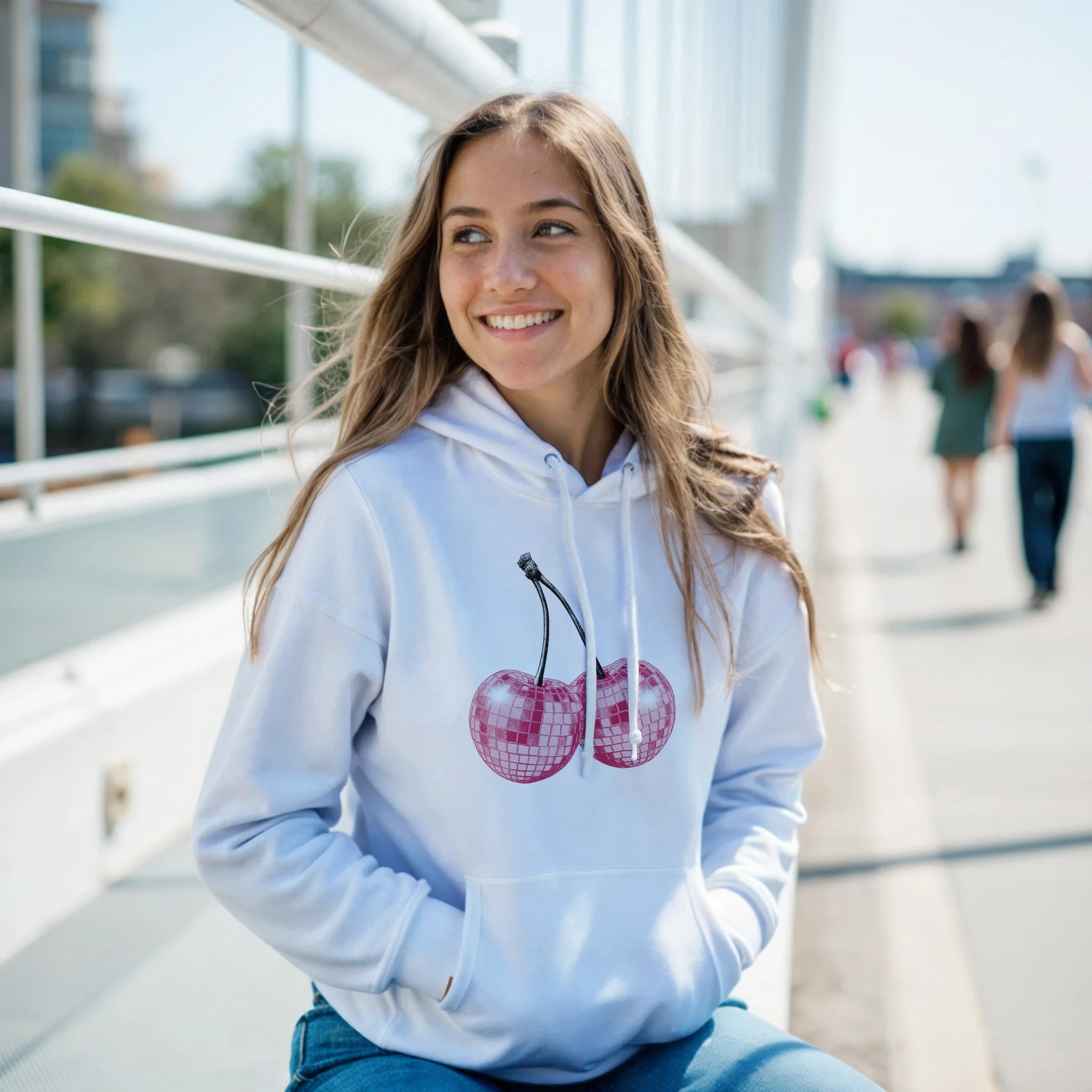Woman wearing Glitter Ball Cherries Jumper Hoodie in light blue with pink cherry graphic and front pouch pocket.