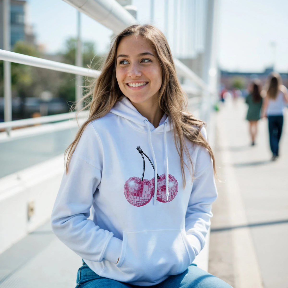 Woman wearing Glitter Ball Cherries Jumper Hoodie in light blue with pink cherry graphic and front pouch pocket.