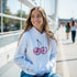 Woman wearing Glitter Ball Cherries Jumper Hoodie in light blue with pink cherry graphic and front pouch pocket.