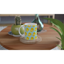 Pastel blue ceramic mug with yellow lemon pattern on wooden coaster next to a small cactus.