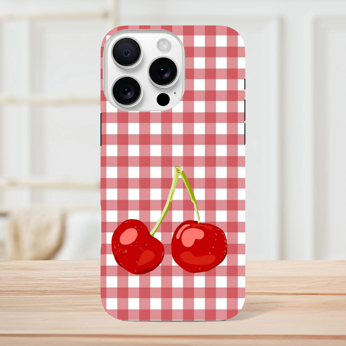 Red and white gingham iPhone case featuring a cute pair of red cherries and tough drop protection for iPhone 13-16.