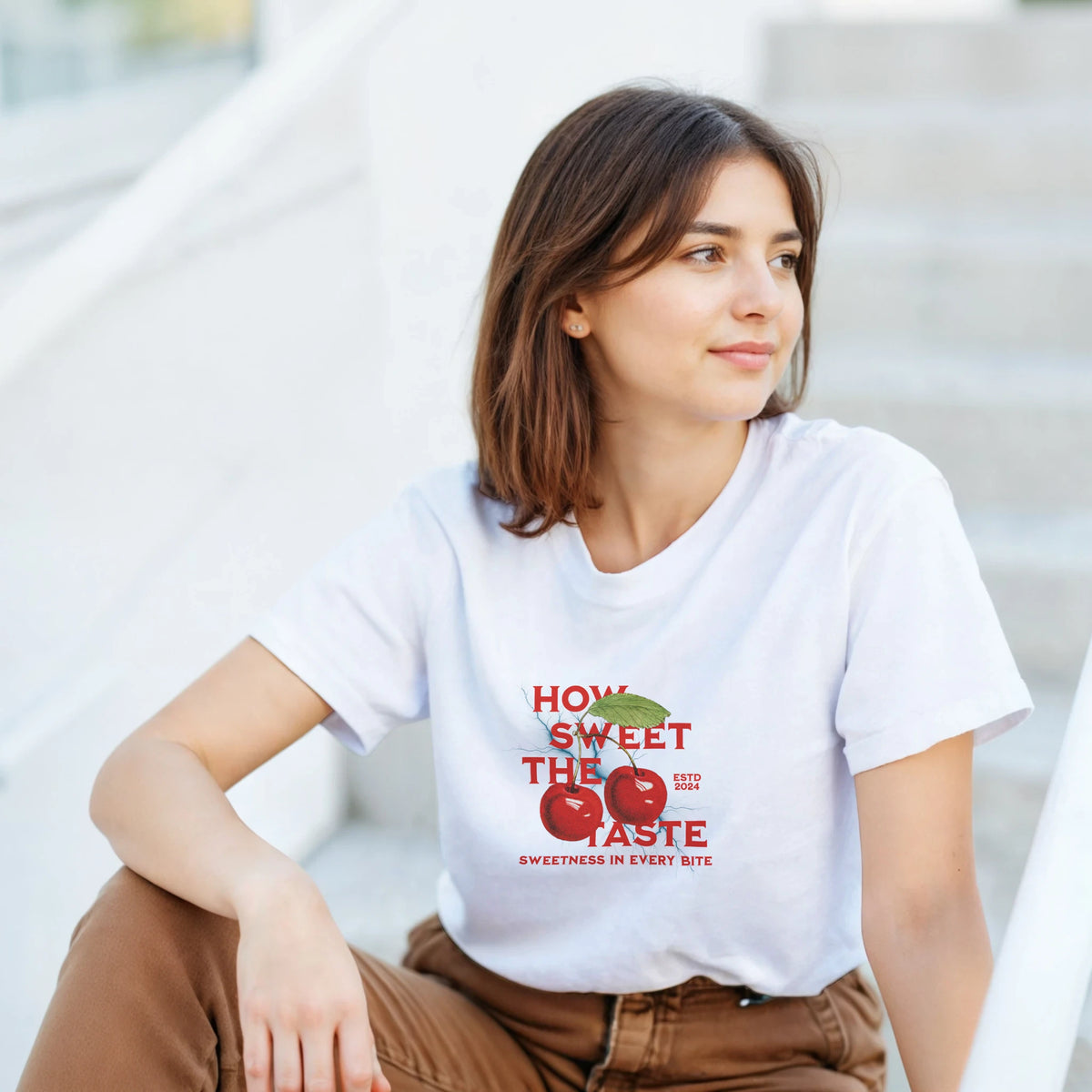 Woman wearing white retro sweet cherry graphic tee featuring red fruit print and "How Sweet The Taste" text.