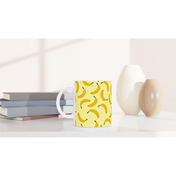 Yellow banana-pattern mug with banana print on a white desk.