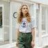 Woman wearing a white Y2K-inspired retro palm tree T-shirt with a colorful circular palm tree graphic.