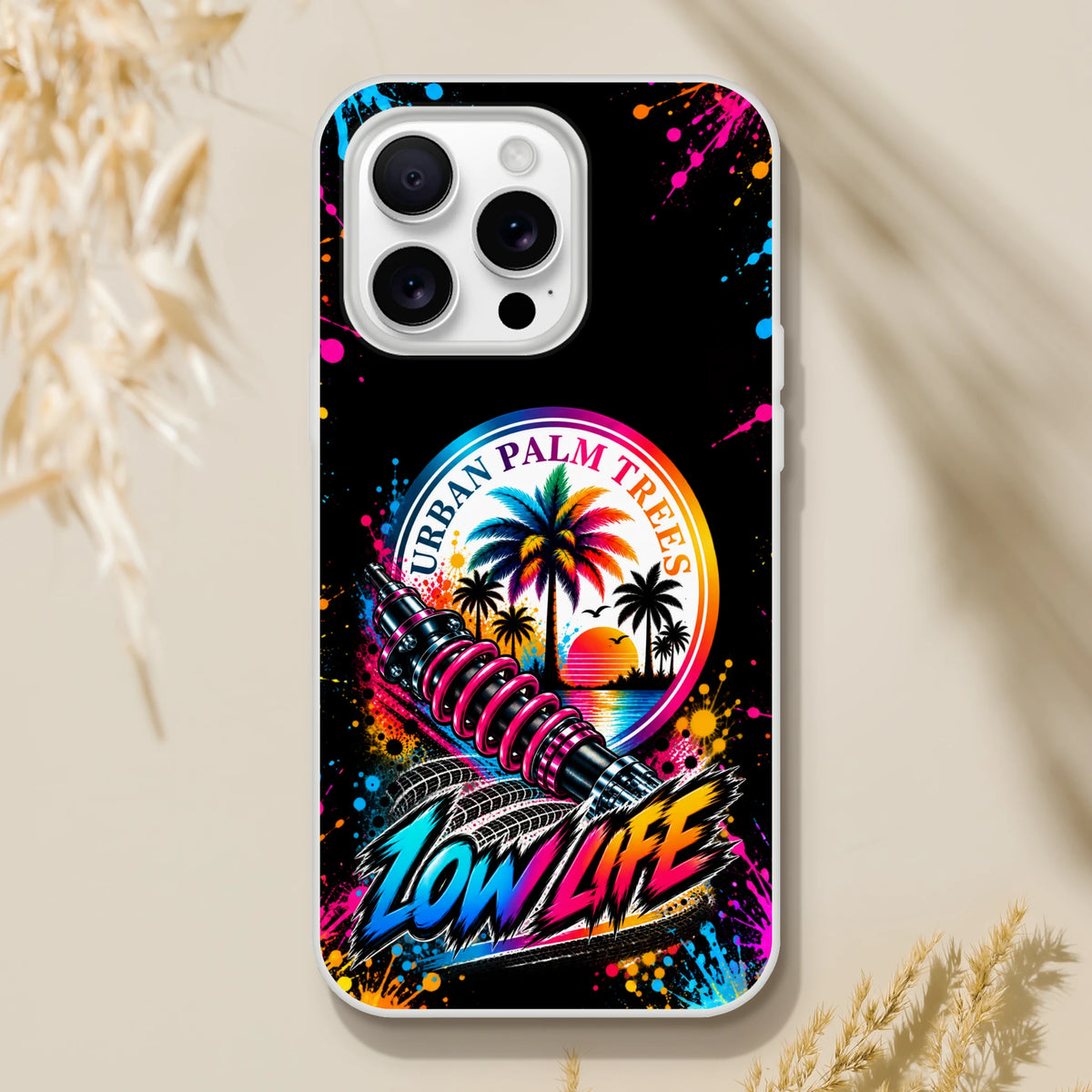 Low Life car culture iPhone case featuring urban palm trees, a pink shock absorber, and colorful splatter art on a black background.