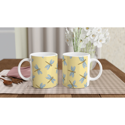 Two yellow dragonfly ceramic mugs with blue dragonfly patterns on a wooden table.