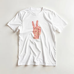 White tee featuring a pink retro peace sign hand graphic made of vintage typography with words like love, hope, and stop war.