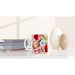 Retro ceramic coffee mug featuring a perfume bottle, colorful floral print, and coquette pink bow design on a white desk.