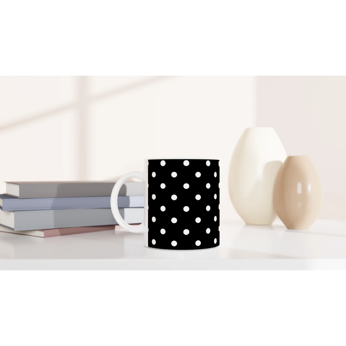 Black ceramic mug with white polka dots on a white desk beside books and vases. Vintage spotty coffee cup for daily brews.