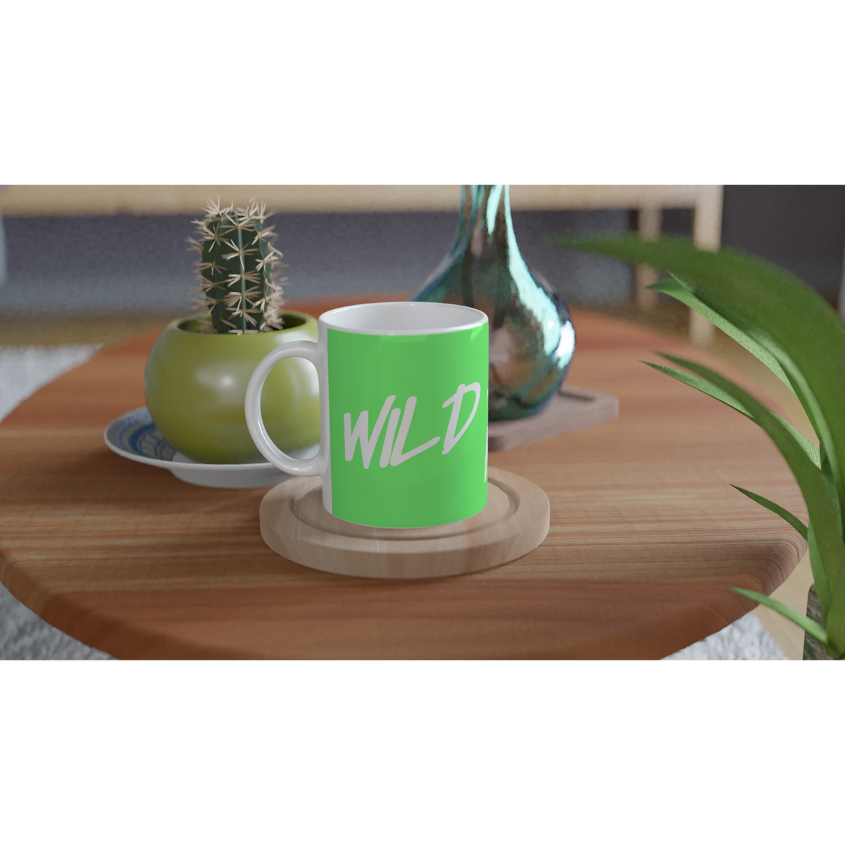 Cute Wild And Free mug with slogan sits on a wooden table beside a cactus and a green vase.