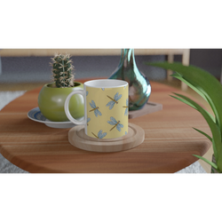 Yellow dragonfly mug with dragonfly print on ceramic cup, on wood table beside a cactus.