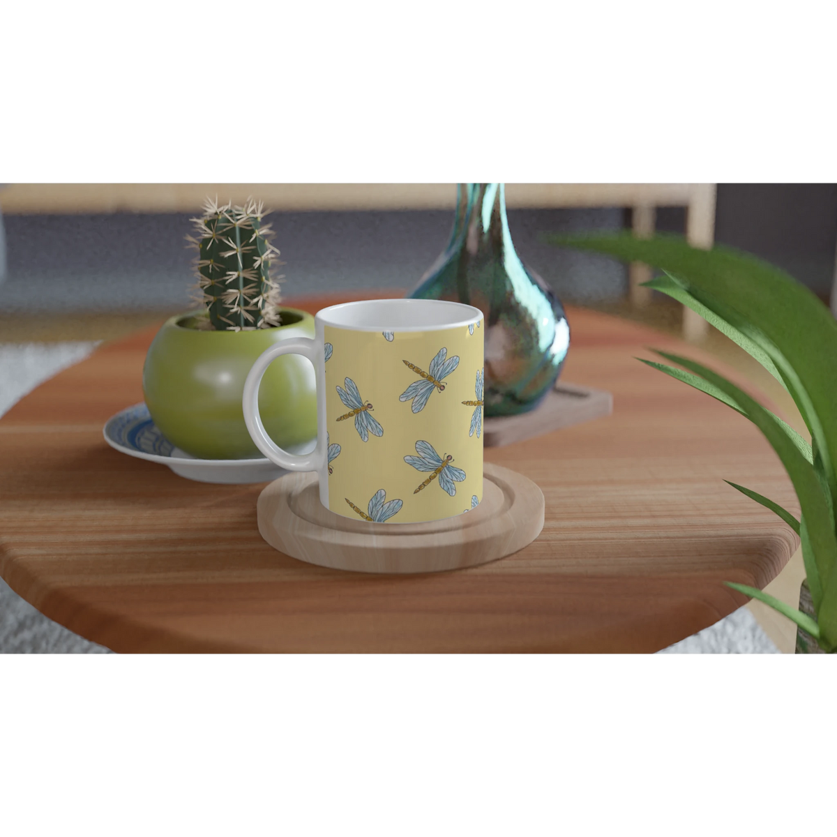 Yellow dragonfly mug with dragonfly print on ceramic cup, on wood table beside a cactus.