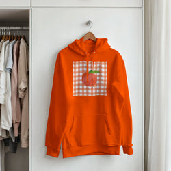 Orange hoodie featuring a retro peach graphic set against a peach and white gingham square, hanging on a wooden hanger.