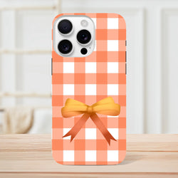 Orange gingham iPhone case featuring a 3D bow accent, offering tough impact resistance for daily commutes and skate sessions.
