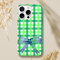 Green gingham iPhone case featuring a purple polka dot bow. Cute coquette tough phone cover for iPhone 13-16.