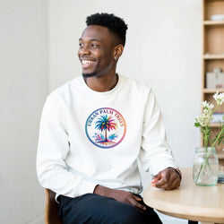 Smiling man in a white pullover with circular palm trees graphic, urban Y2K streetwear vibe