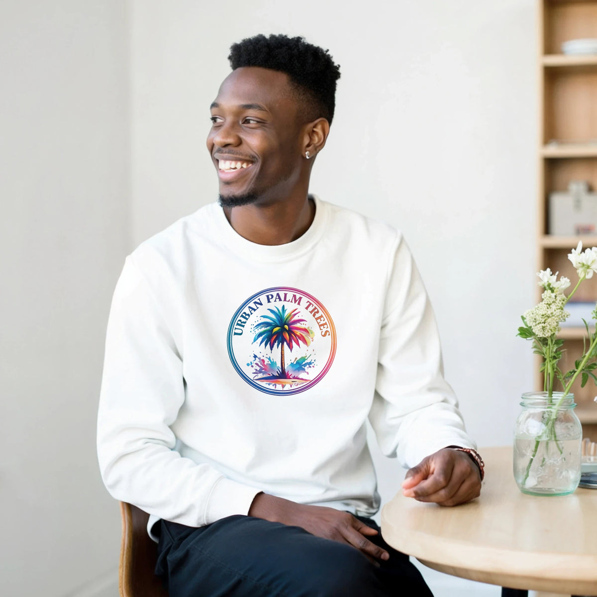 Smiling man in a white pullover with circular palm trees graphic, urban Y2K streetwear vibe