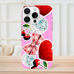 Pink iPhone case featuring sticker-style cherries, heart-patterned bow, disco balls, and faceted red hearts in a bold Y2K design.