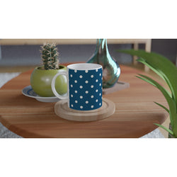 Retro navy blue ceramic mug with white polka dots sits on a wooden coaster beside a cactus plant.