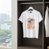 White t-shirt with 'Summer Living Sunshine & Palm Trees' design hanging in a wardrobe.