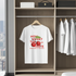 White t-shirt with red and green graphic design hanging in a wardrobe.