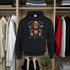 Black hoodie with a teddy bear graphic in a wardrobe setting