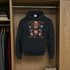 Black hoodie with a teddy bear graphic hanging in a closet.