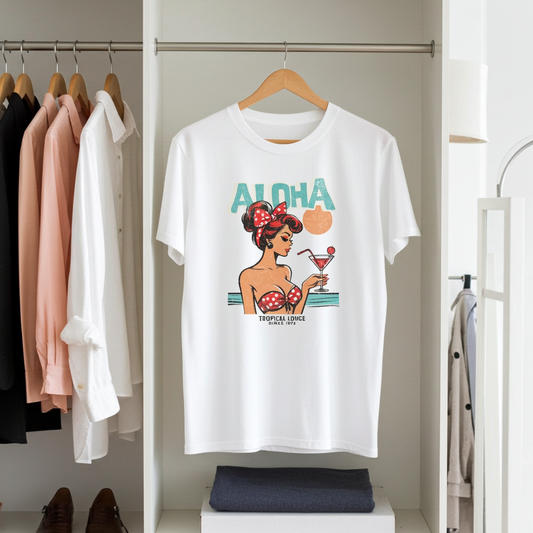 White t-shirt with a graphic design of a woman holding a cocktail, labeled 'Aloha', hanging on a rack in a closet.